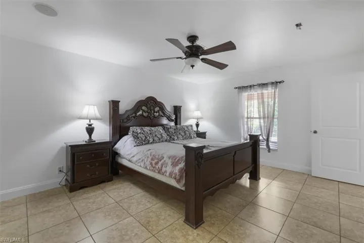 Bedroom with light tile patterned flooring, ceiling fan, and baseboards
