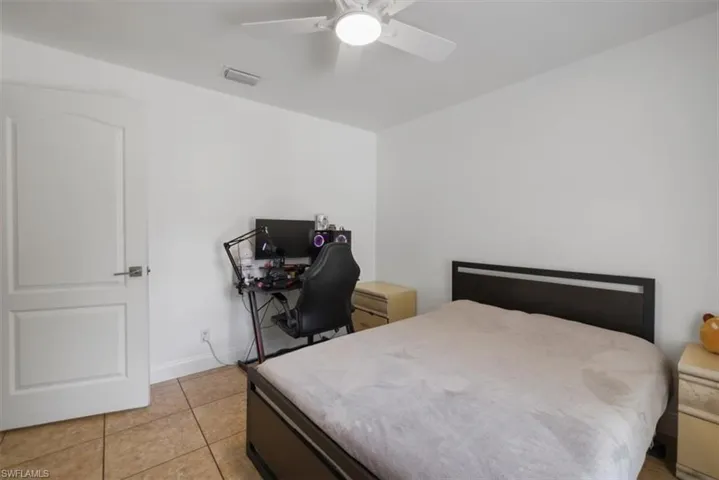 Bedroom featuring baseboards, visible vents, light tile patterned floors, and ceiling fan