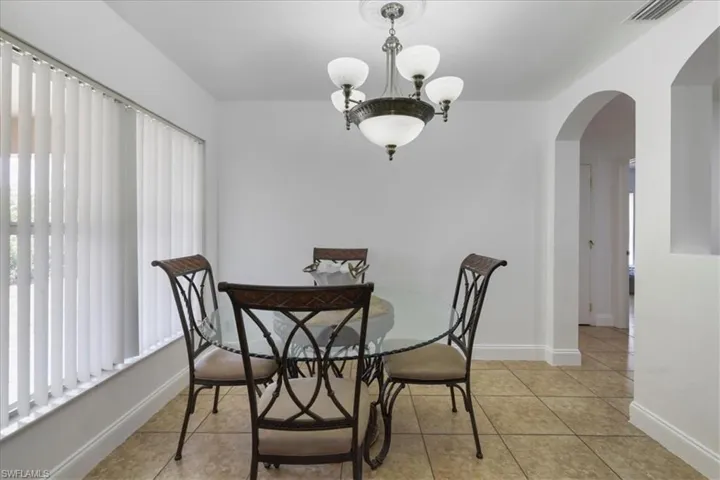 Dining room with light tile patterned floors, visible vents, plenty of natural light, and arched walkways