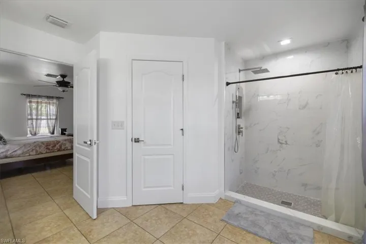 Bathroom featuring a shower with curtain, tile patterned floors, visible vents, and connected bathroom