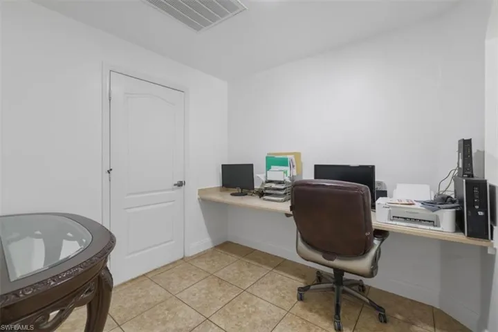 Home office featuring light tile patterned flooring, visible vents, and baseboards