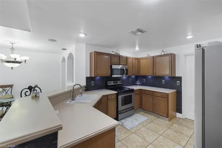 Kitchen featuring a chandelier, stainless steel appliances, tasteful backsplash, visible vents, and a peninsula