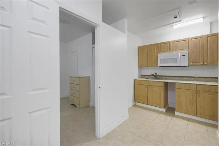 Kitchen featuring a sink, white microwave, brown cabinets, and light countertops