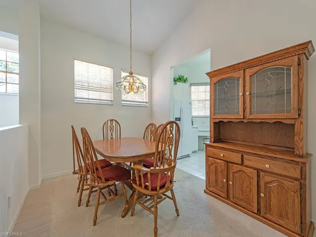 Dining space with plenty of natural light, a notable chandelier, vaulted ceiling, and light colored carpet
