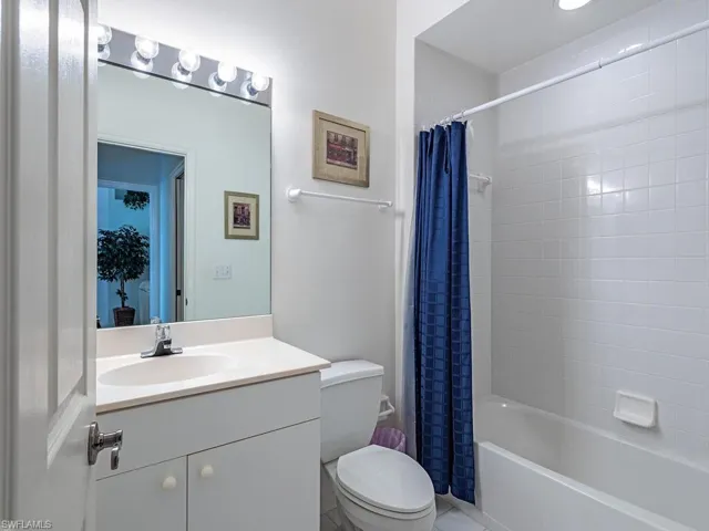 Full bathroom with vanity, shower / bath combination with curtain, and toilet