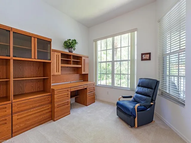 Home office featuring baseboards, built in study area, and light carpet