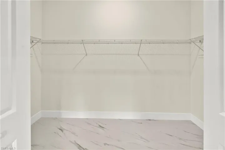 Walk in closet with light marble finish flooring