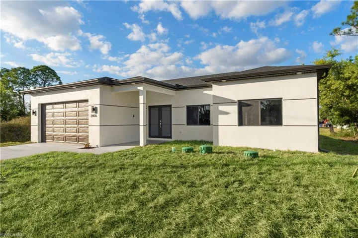 View of front facade with a garage, a front lawn, concrete driveway, and stucco siding
