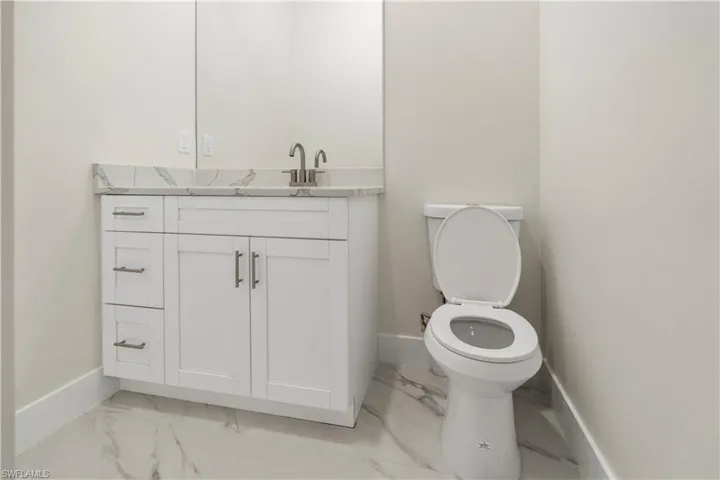 Half bath with vanity and light marble finish floors