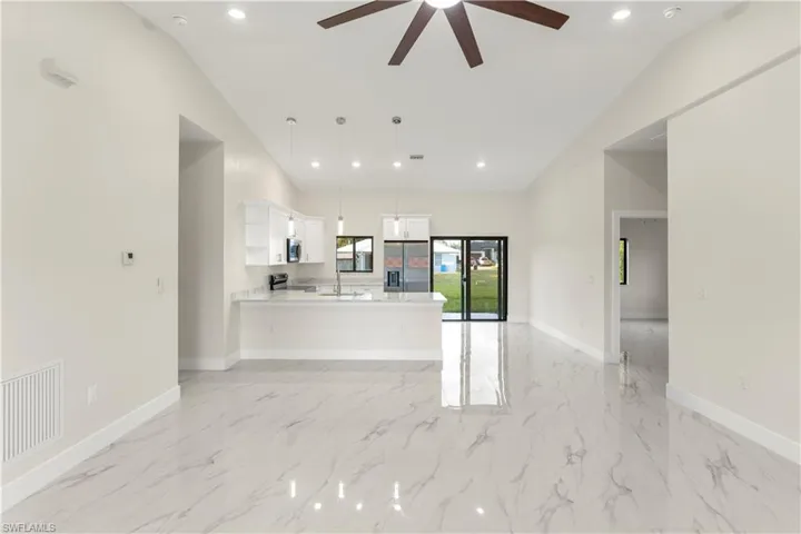 Unfurnished living room with light marble finish floors, a ceiling fan, and recessed lighting