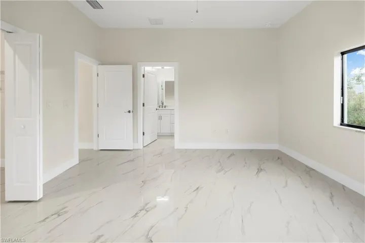 Unfurnished bedroom with ensuite bathroom and light marble finish flooring