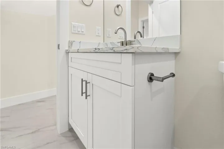 Half bath with vanity and light marble finish floors