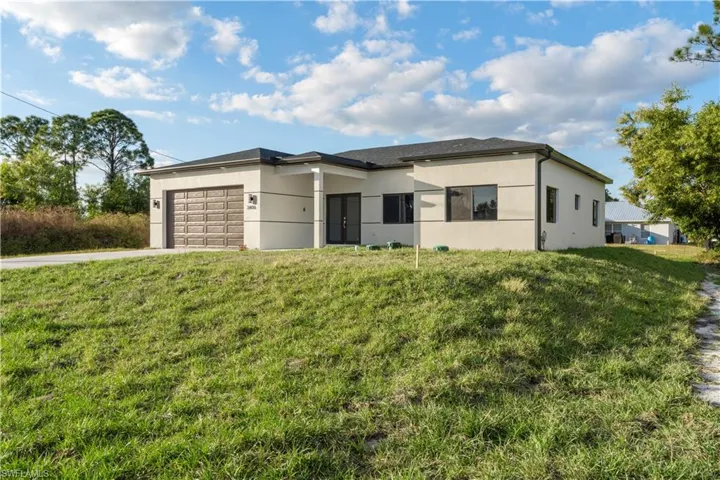 View of front of home featuring a front lawn, stucco siding, and an attached garage