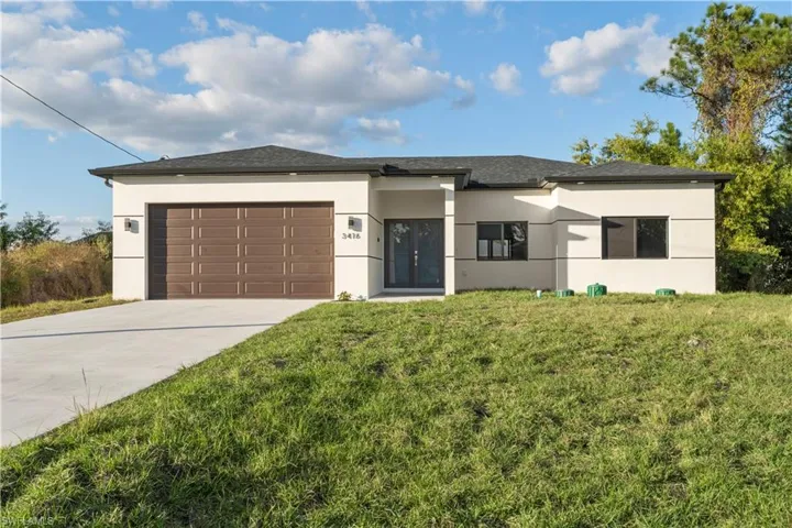 View of front of house with stucco siding, a garage, concrete driveway, and a front lawn