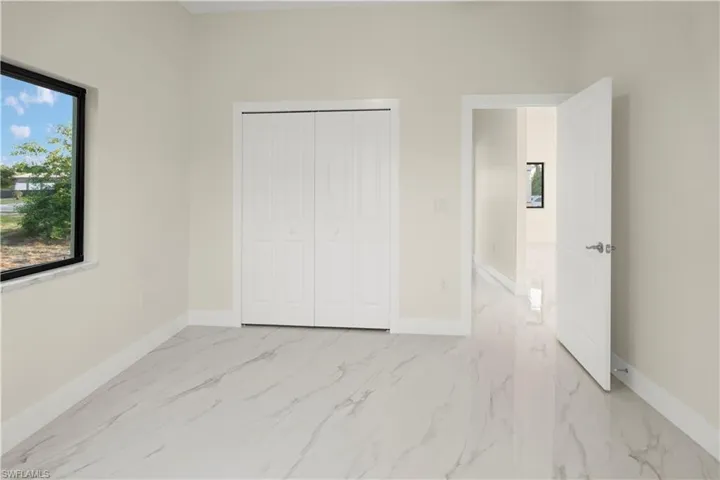 Unfurnished bedroom with light marble finish floors and a closet