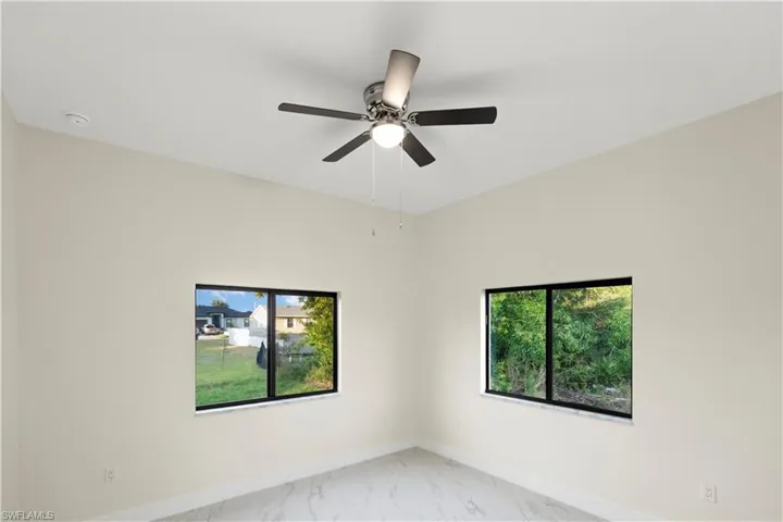Spare room featuring light marble finish flooring, plenty of natural light, and a ceiling fan