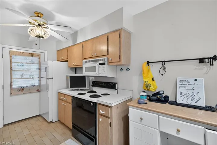 Kitchen featuring electric range, light countertops, a ceiling fan, and white microwave