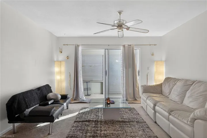 Living area with carpet floors, ceiling fan, and a textured ceiling