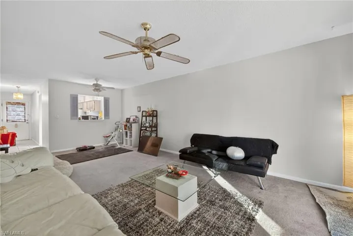 Carpeted living room featuring baseboards and a ceiling fan