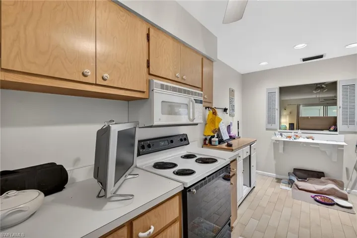 Kitchen featuring range with electric stovetop, ceiling fan, light countertops, white microwave, and recessed lighting