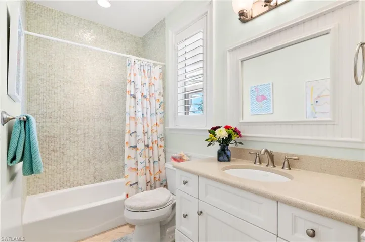 Bathroom with vanity, shower / bath combination with curtain, light tile patterned floors, and recessed lighting