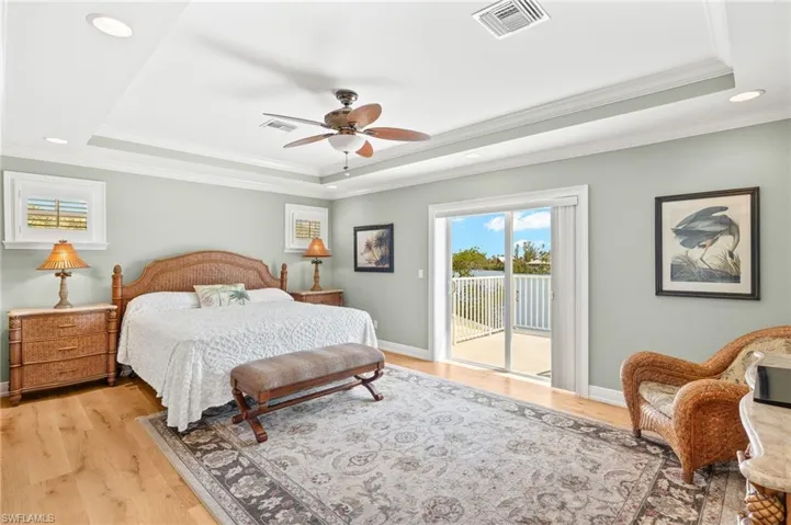 Bedroom with a tray ceiling, recessed lighting, crown molding, wood finished floors, and ceiling fan