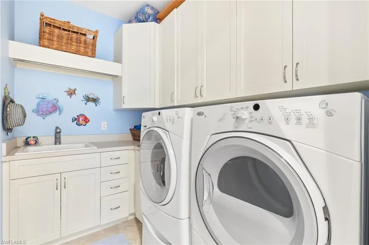 Laundry area featuring light tile patterned floors, separate washer and dryer, and cabinet space