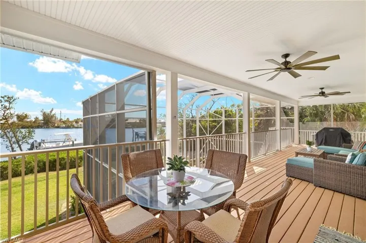 Sunroom featuring outdoor dining area, a deck with water view, an outdoor living space, and ceiling fan