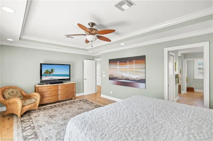 Bedroom featuring a raised ceiling, ornamental molding, recessed lighting, a ceiling fan, and light wood-style floors