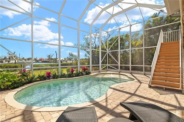Outdoor pool featuring a sunroom, a lanai, stairs, and a patio area