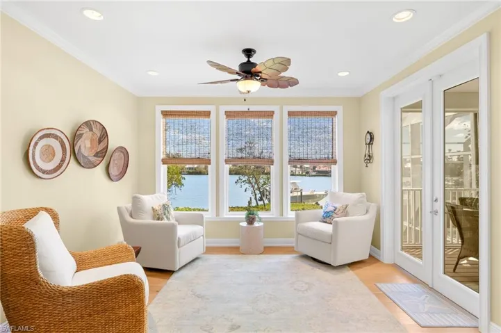 Living area featuring crown molding, light wood finished floors, a ceiling fan, a water view, and recessed lighting
