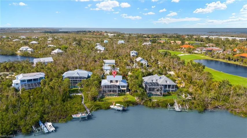 Aerial view of residential area featuring a nearby body of water and a golf course
