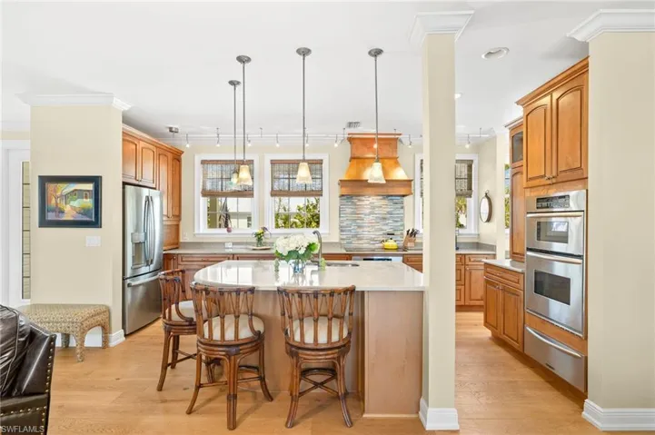 Kitchen with a breakfast bar, pendant lighting, light wood-type flooring, appliances with stainless steel finishes, and decorative backsplash