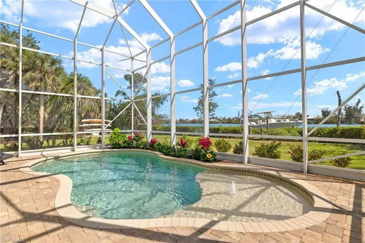 Outdoor pool with glass enclosure, a sunroom, and a water view