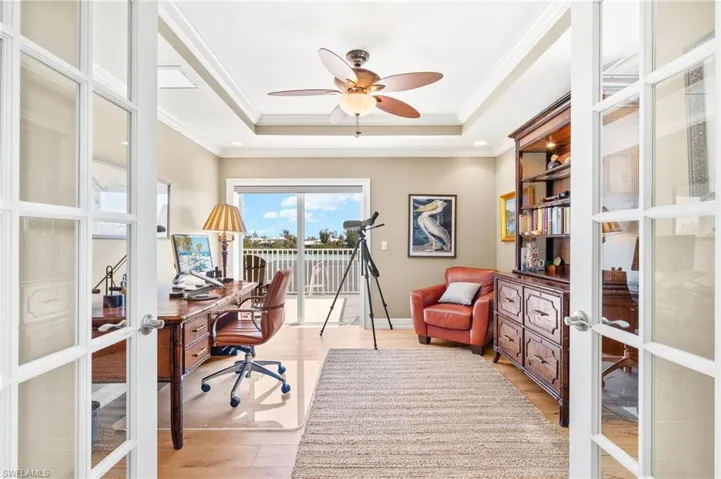 Home office featuring french doors, light wood-type flooring, a raised ceiling, crown molding, and ceiling fan