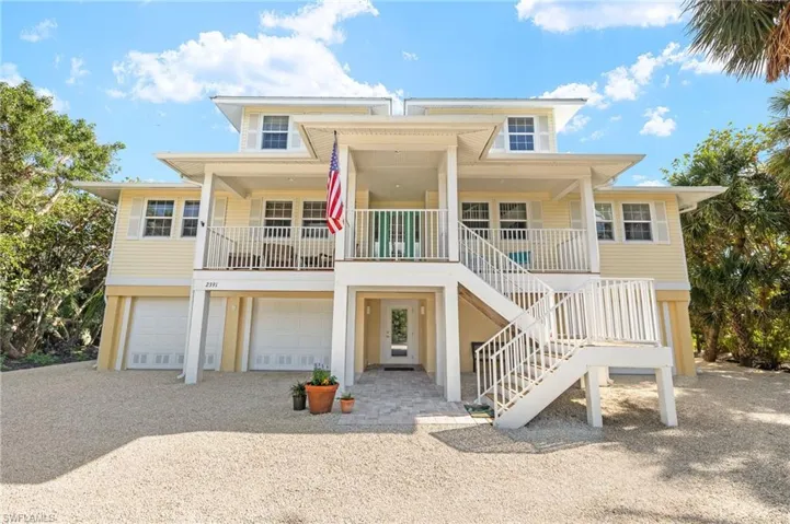 View of front of house featuring stairs, covered porch, driveway, and a garage