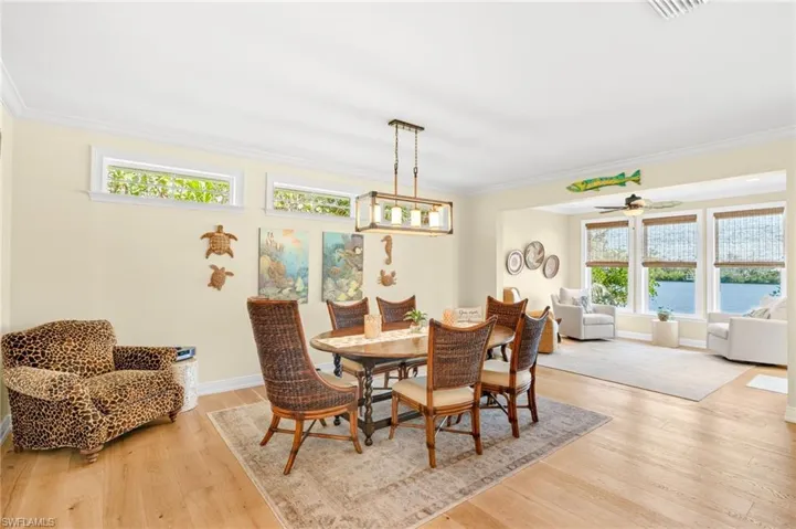 Dining area with light wood-style floors, ornamental molding, a ceiling fan, and a water view