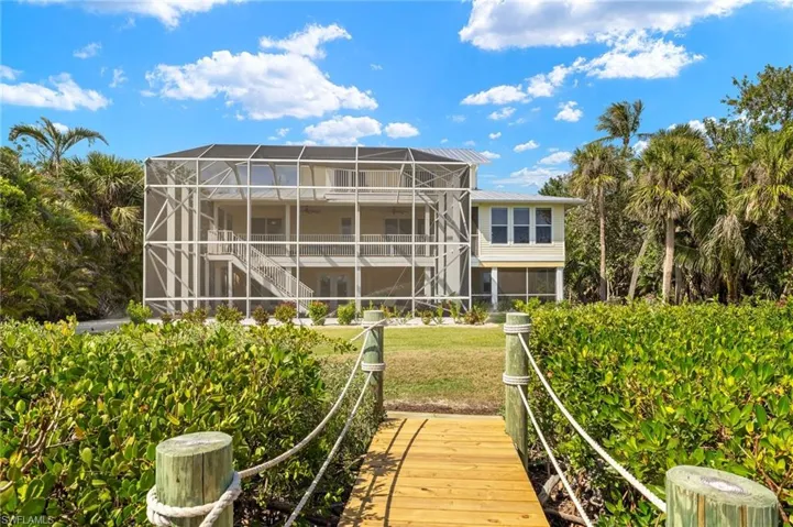 Back of property with stairs, a lanai, a sunroom, and a yard