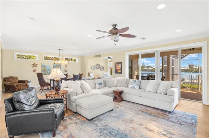 Living room featuring healthy amount of natural light, ornamental molding, wood finished floors, recessed lighting, and a water view