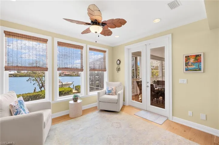 Living area with ornamental molding, a water view, light wood-style floors, french doors, and recessed lighting
