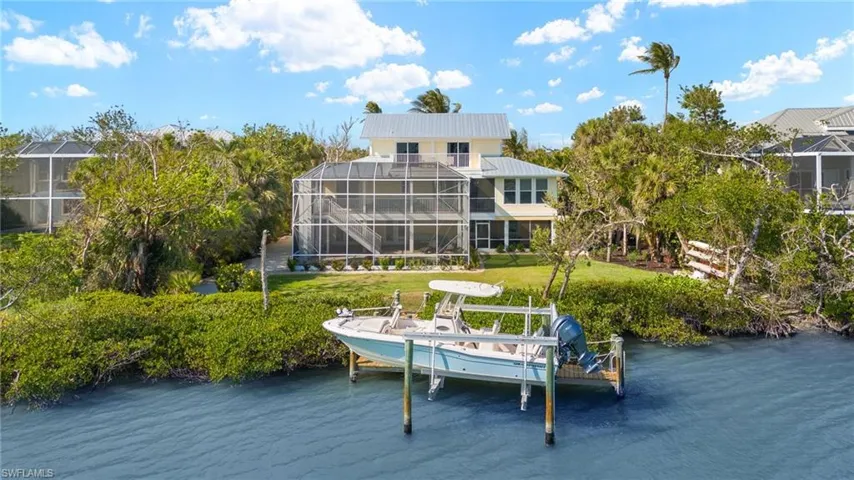 Dock area featuring boat lift, a lanai, a water view, and a lawn