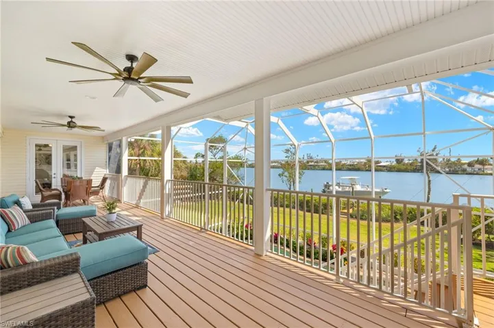 Wooden terrace featuring ceiling fan, a sunroom, glass enclosure, a water view, and french doors