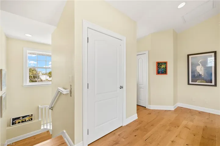 Hallway with an upstairs landing, light wood finished floors, and recessed lighting
