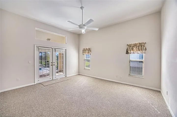 Carpeted spare room with french doors and a ceiling fan