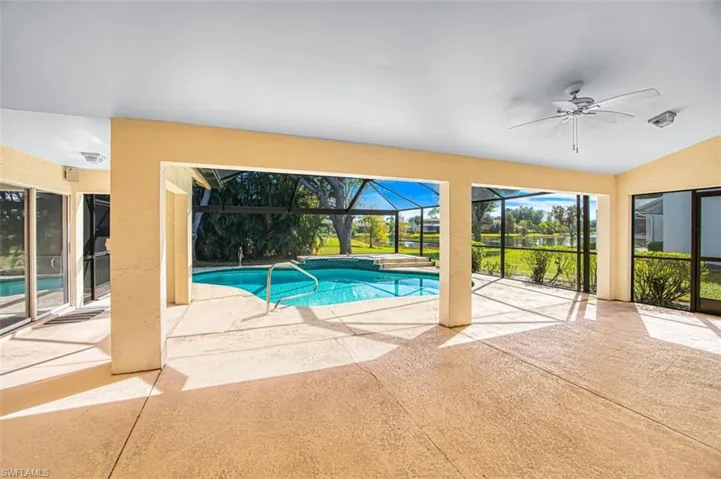 Swimming pool featuring a patio area, a sunroom, glass enclosure, and a water view