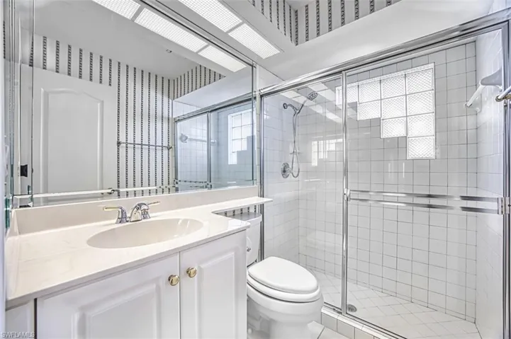 Bathroom with vanity, a stall shower, and wallpapered walls