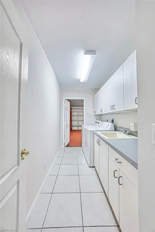 Laundry room featuring cabinet space, sink, light tile patterned floors, and separate washer and dryer