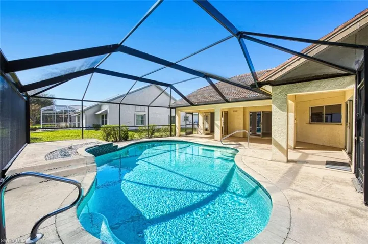 Swimming pool featuring a sunroom, a patio, and glass enclosure