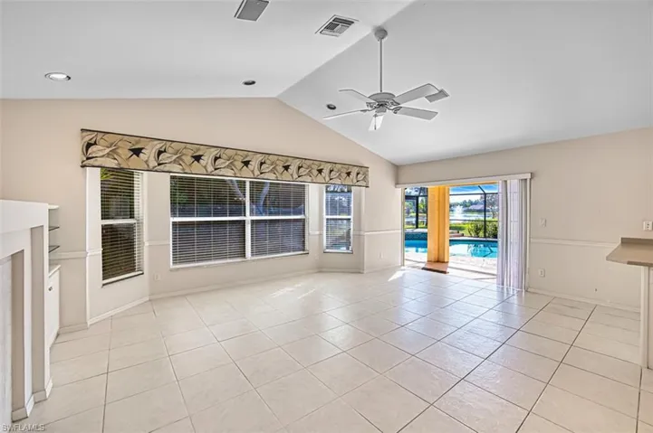Unfurnished living room with vaulted ceiling, light tile patterned floors, and a ceiling fan