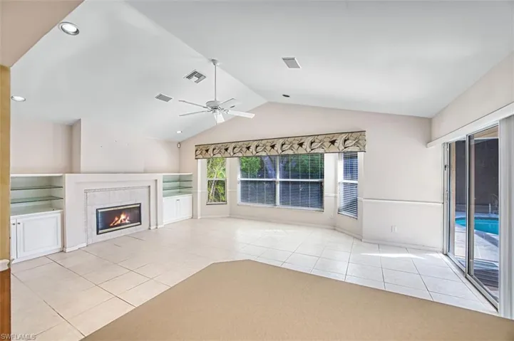Unfurnished living room with light tile patterned floors, lofted ceiling, a tile fireplace, ceiling fan, and recessed lighting